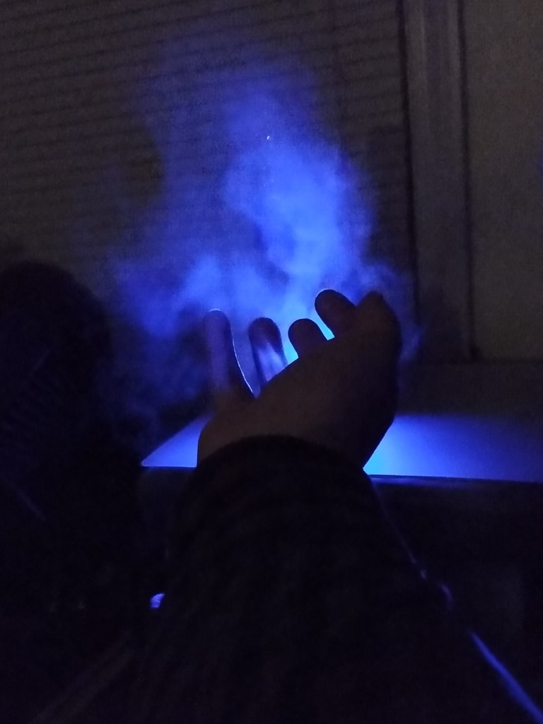 In a dark room, I hold glowing blue mist in my hand.